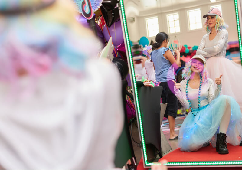 Party hosts posing for a photo in front of a photo booth mirror