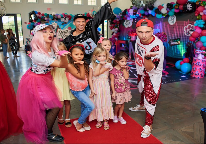 Party hosts and children posing for a photo in front of a photo booth
