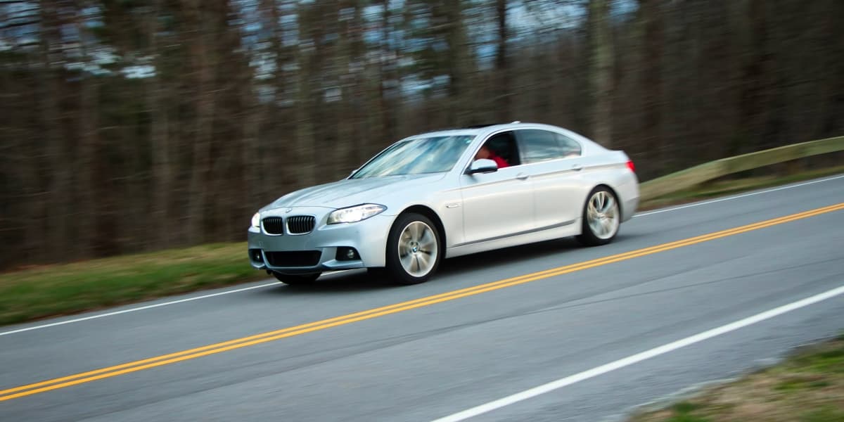 White sedan driving a tree-lined curved road in Tennessee