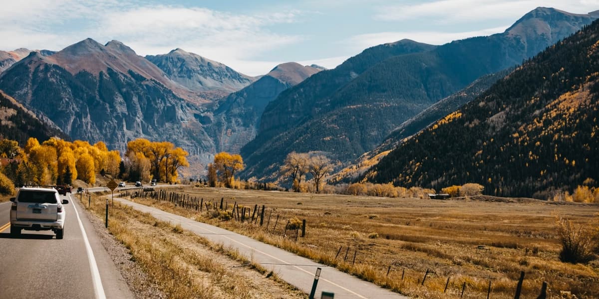 Car driving a scenic mountain highway through Colorado's San Juan Mountains in fall