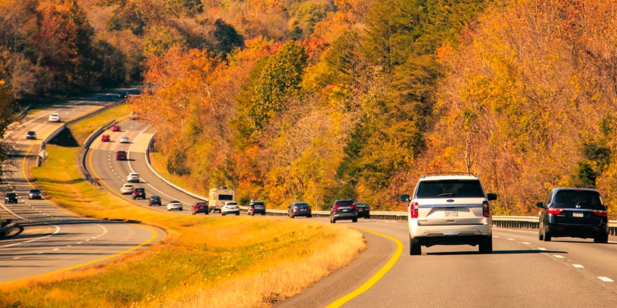 Cars driving a curved highway through fall foliage in Virginia