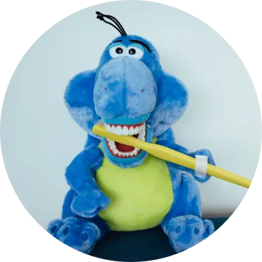 Photo of a stuffed animal with realistic teeth and a large toothbrush