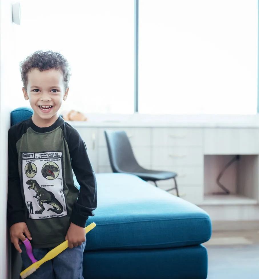 Photo of a smiling boy holing a large toothbrush