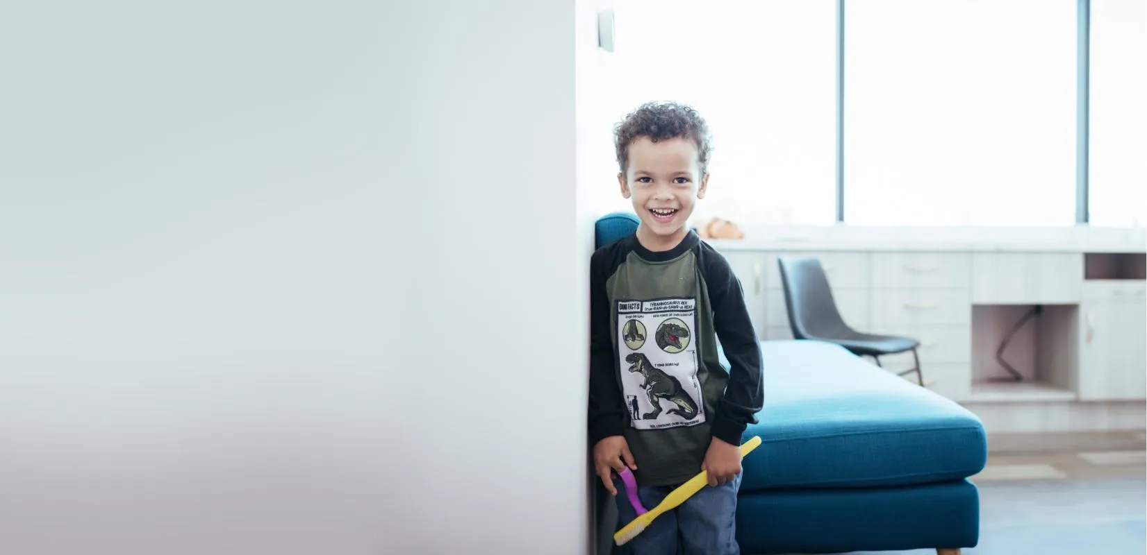 Photo of a smiling boy holding a large toothbrush