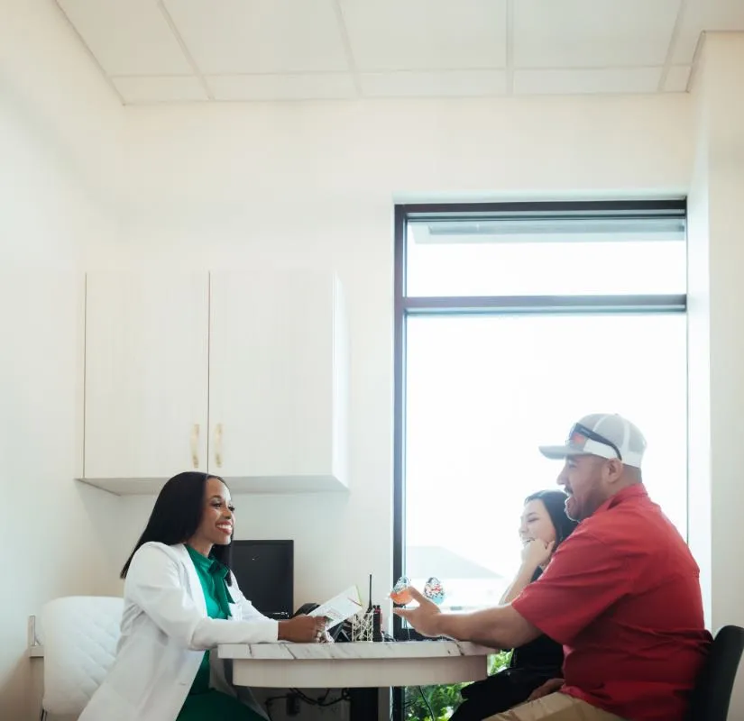 Photo of Dr. Marshall talking with a dad and his daughter at a conference table