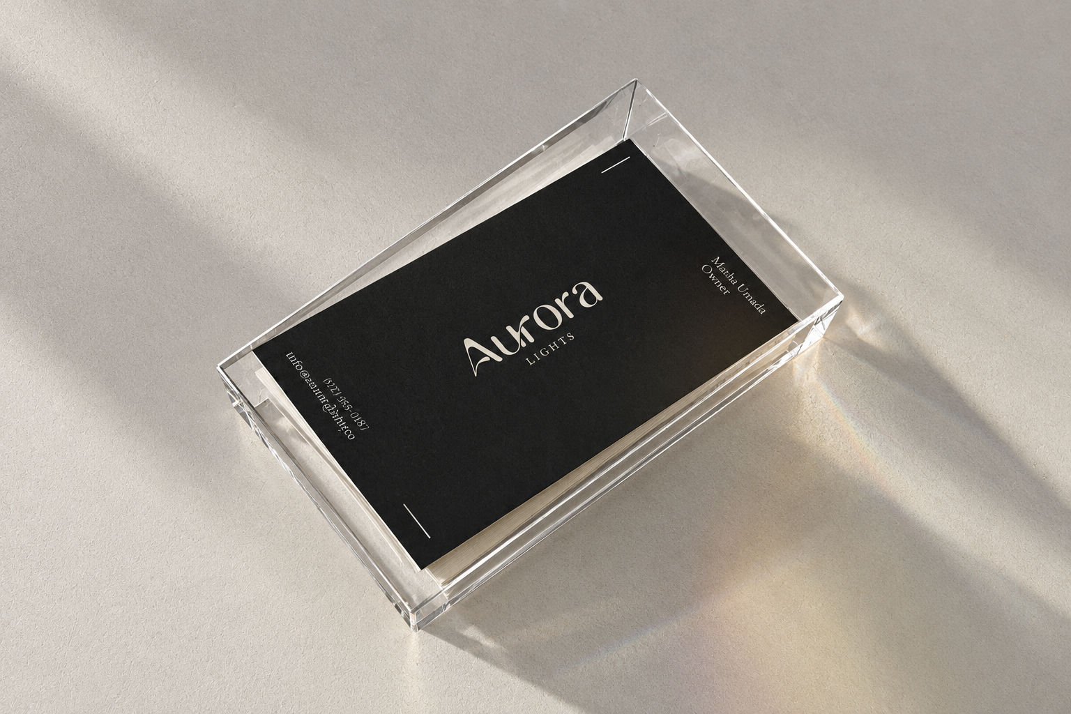 Black Aurora business card in a clear acrylic holder, catching afternoon light