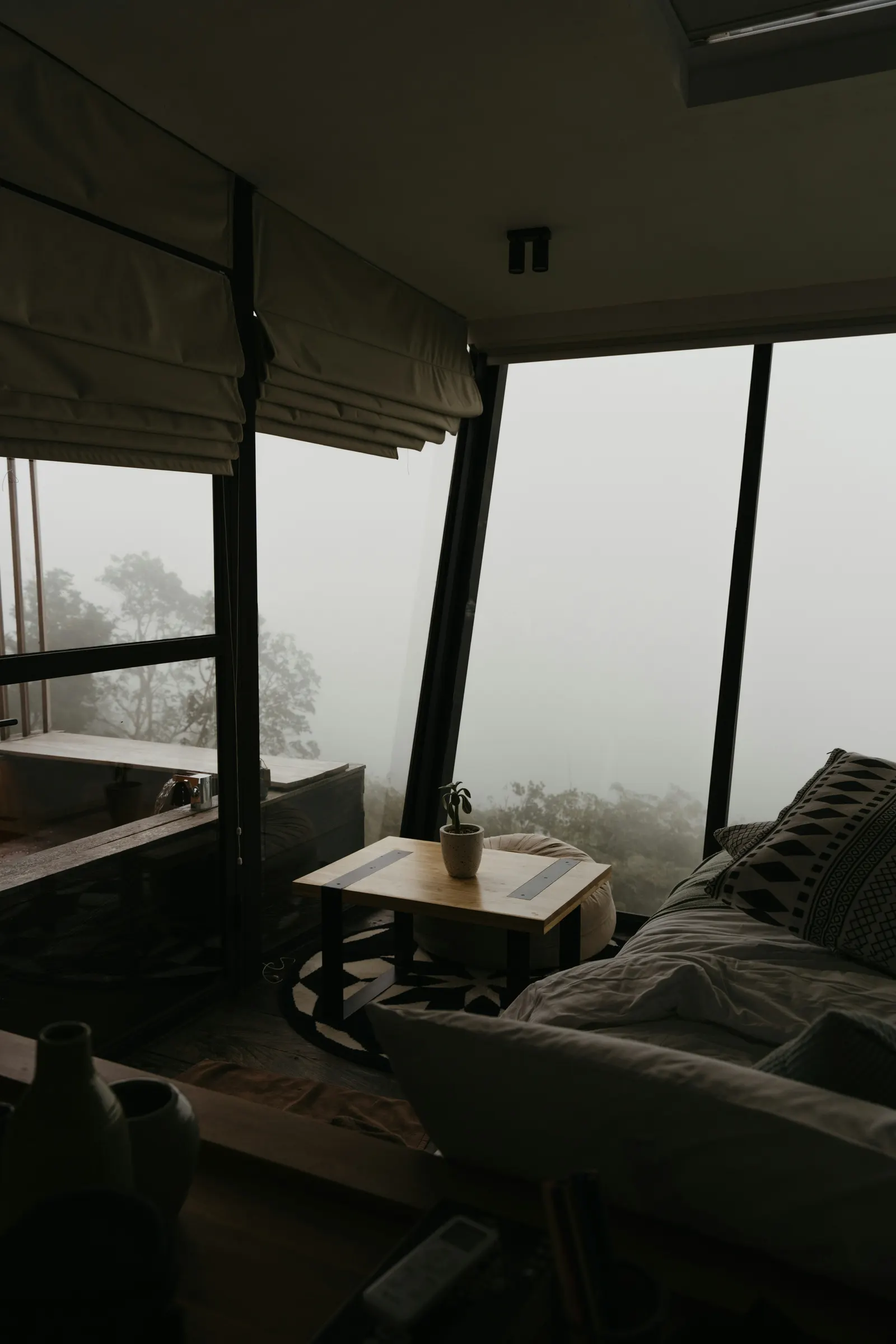 A glass-walled mountain retreat looking out over trees lost in morning fog