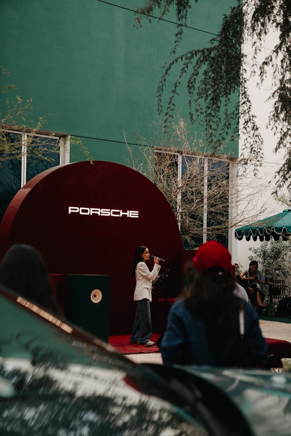 A woman sings on a stage with a porsche logo.