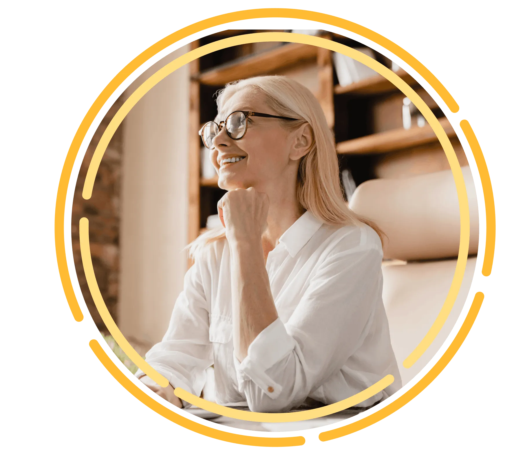 Smiling older woman wearing glasses, seated at a desk in a bright home office