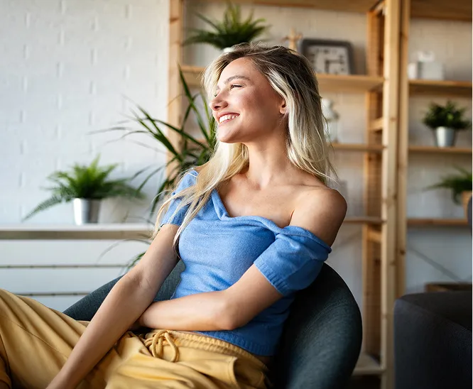 Woman sitting comfortably in a chair, smiling in a bright, modern living space
