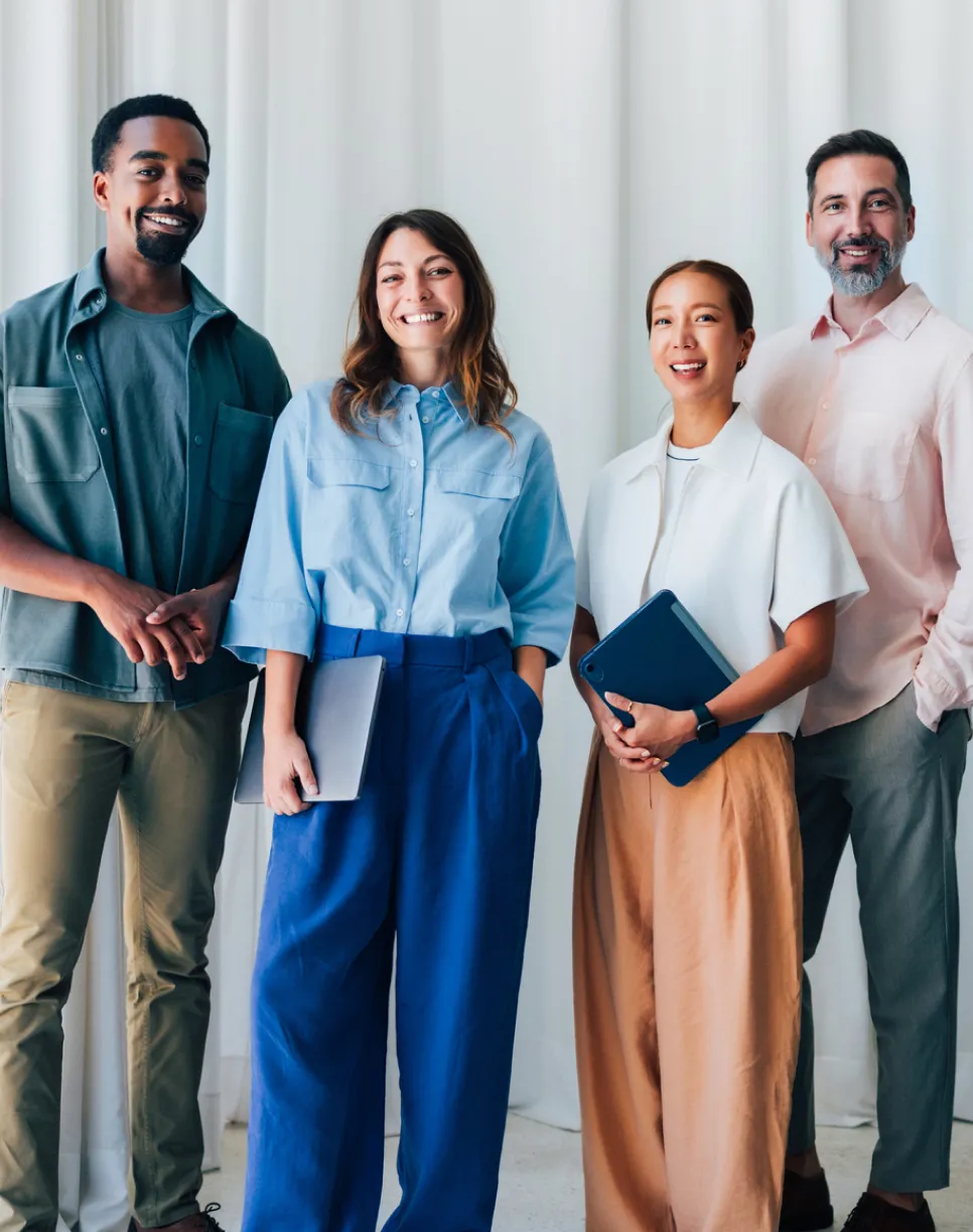 Group of four professionals smiling and standing together in a bright office setting