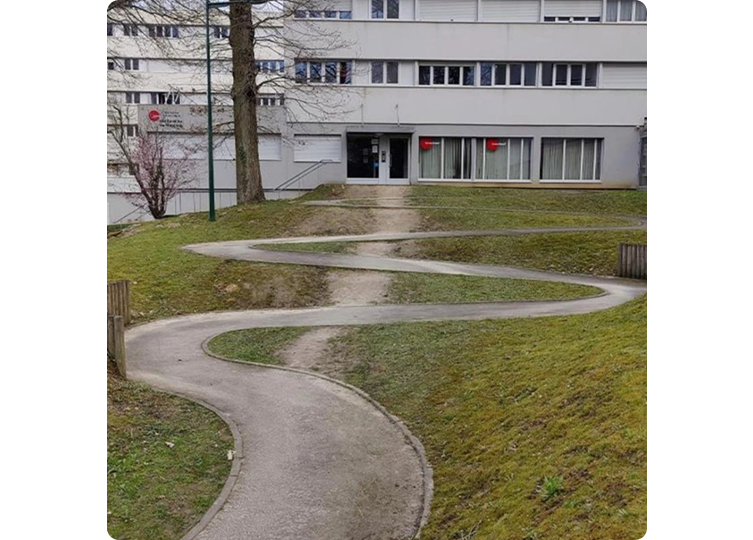 Ein gepflasterter Weg in Serpentinen mit einem Trampelpfad als Abkürzung