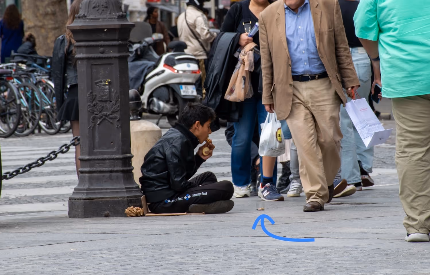 a boy sat on the floor with a transparent cup to have people give him money