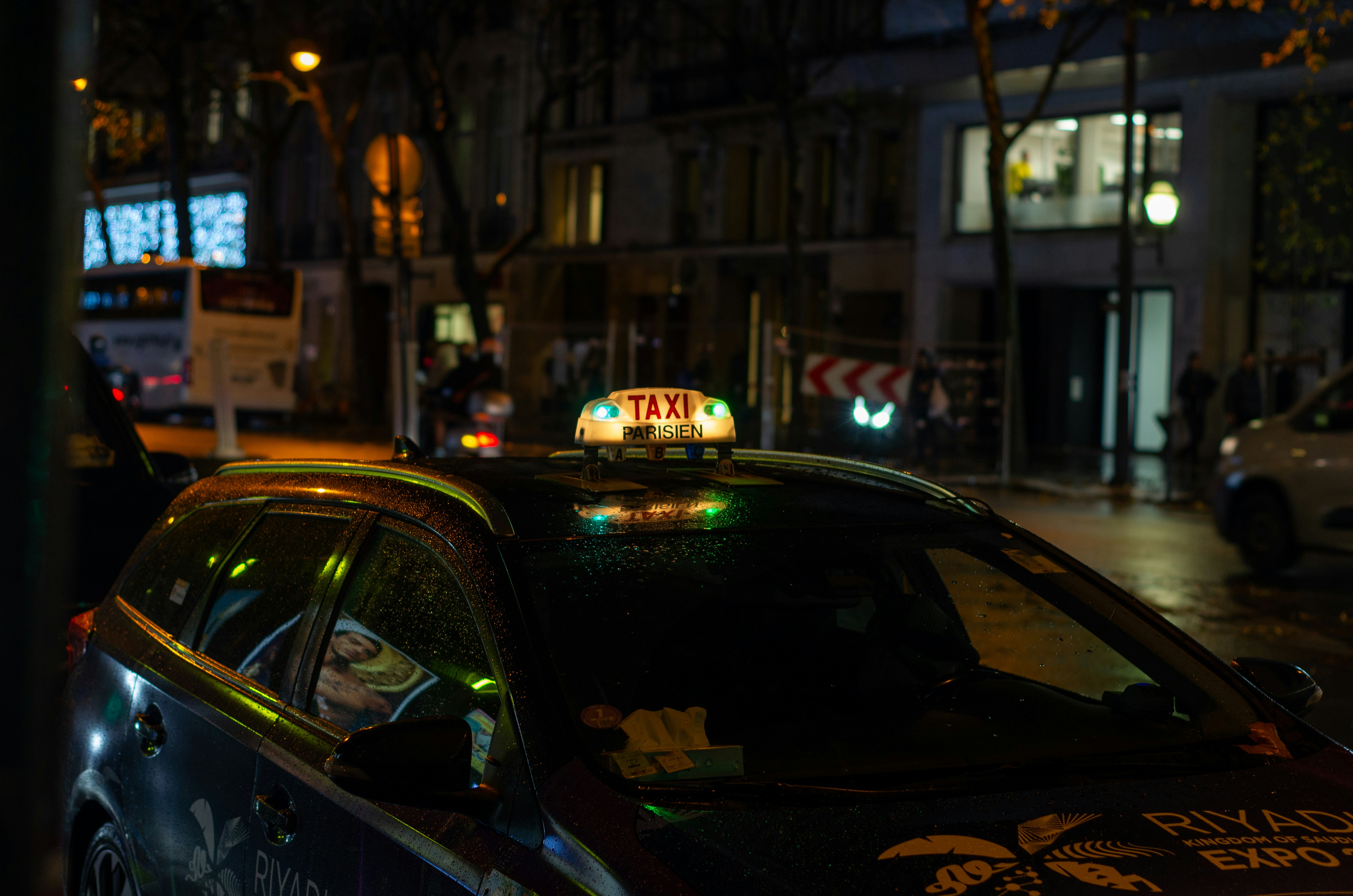 A taxi at night with it's sign turned on in green