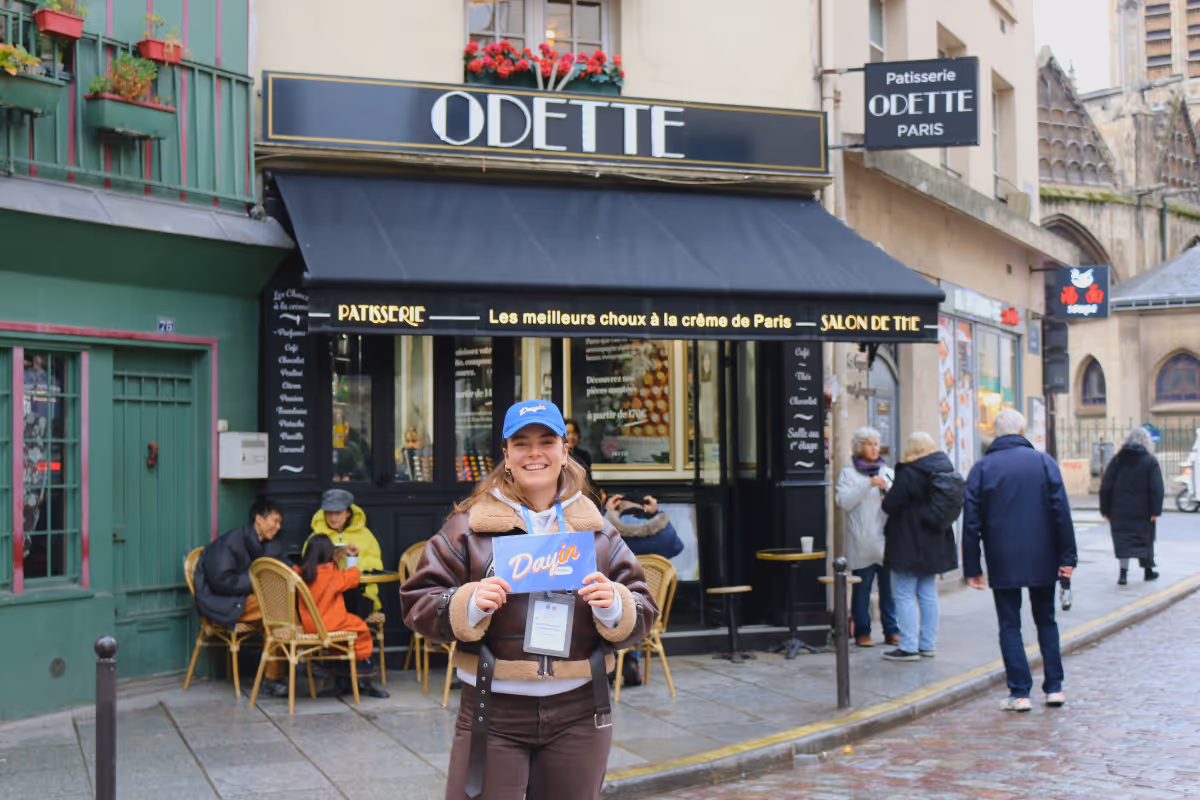 Guide holding a blue sign saying "Dayin" and "Connecting France" in front of a big and colorful glass-bubble modern sculpture.
