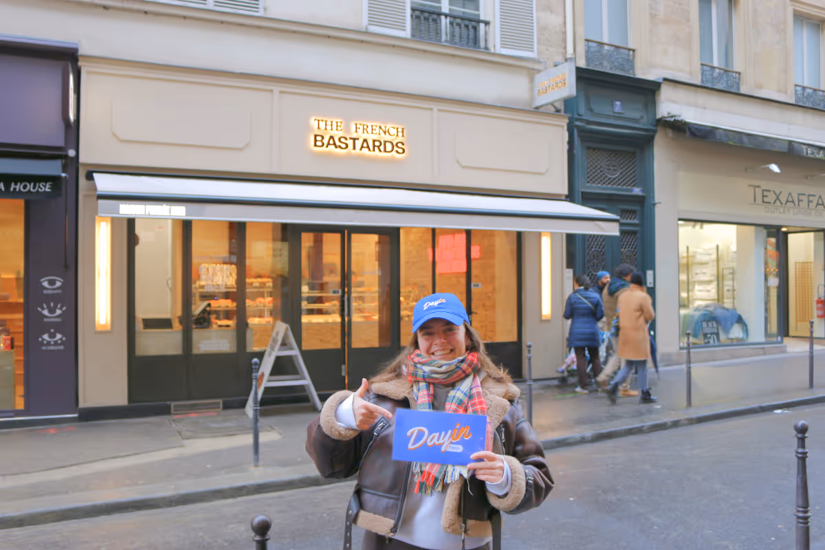 Guide holding a blue sign saying "Dayin" and "Connecting France" in front of a big and colorful glass-bubble modern sculpture.
