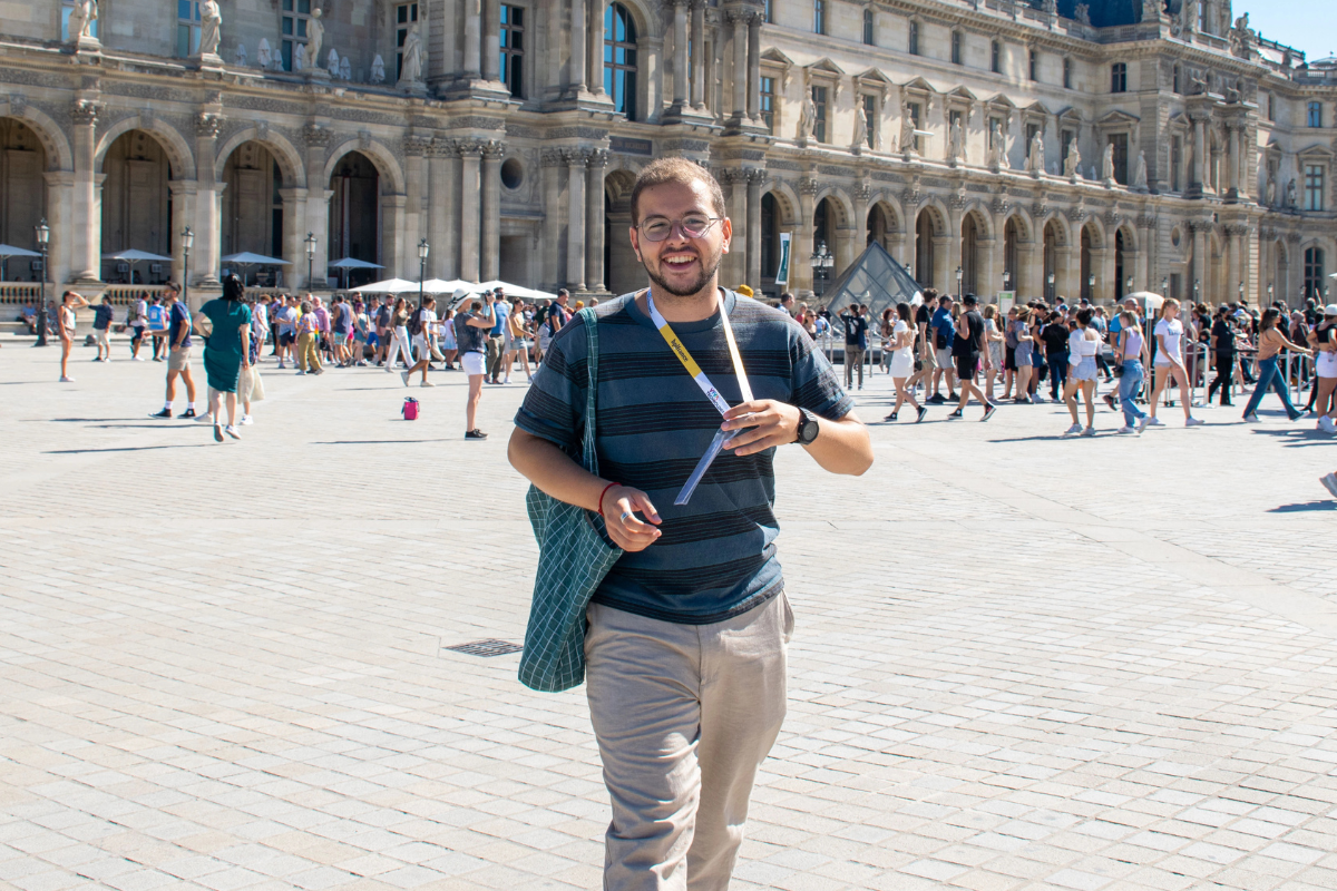 Guide holding a blue sign saying "Dayin" and "Connecting France" in front of a big and colorful glass-bubble modern sculpture.