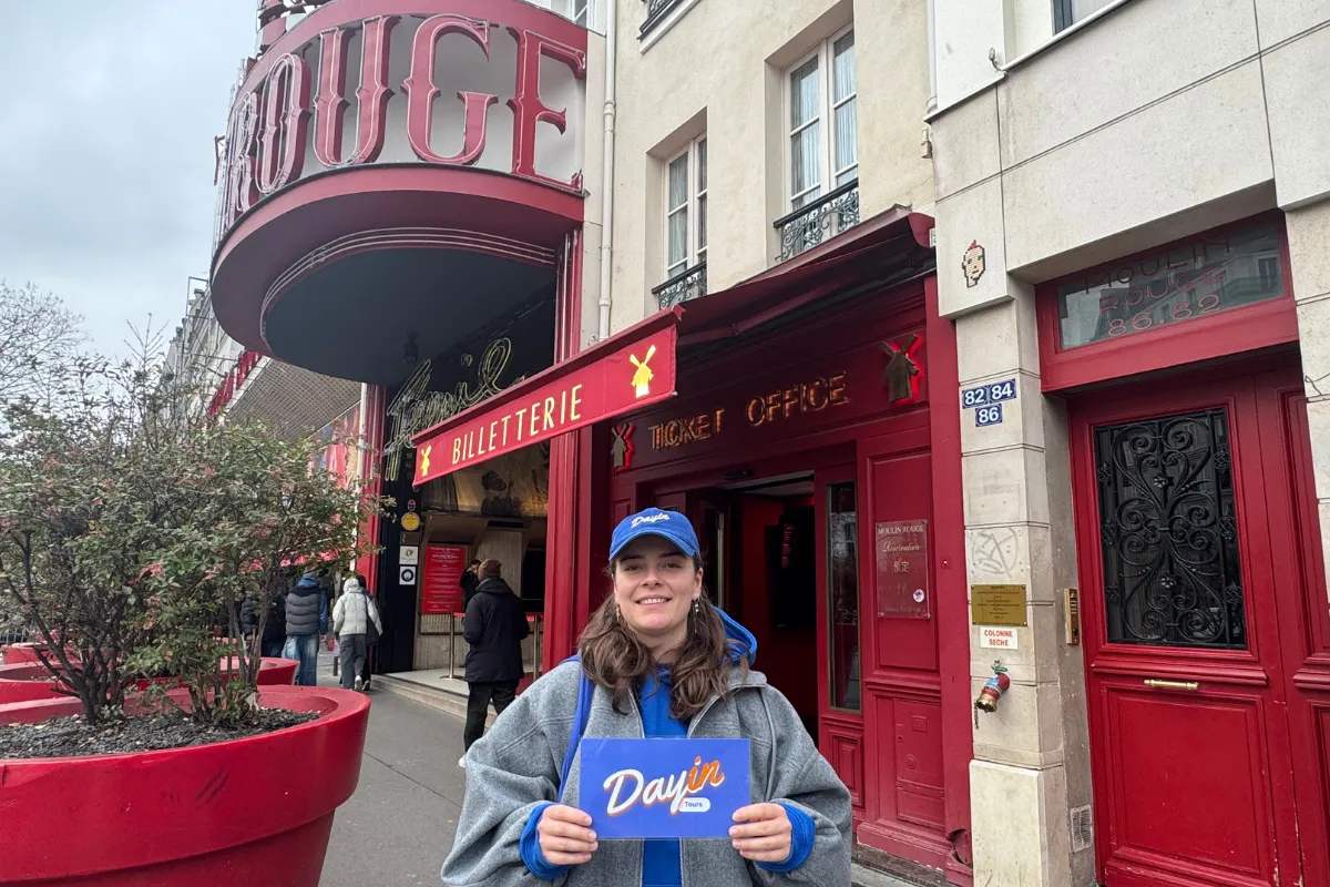 Guide holding a blue sign saying "Dayin" and "Connecting France" in front of a big and colorful glass-bubble modern sculpture.