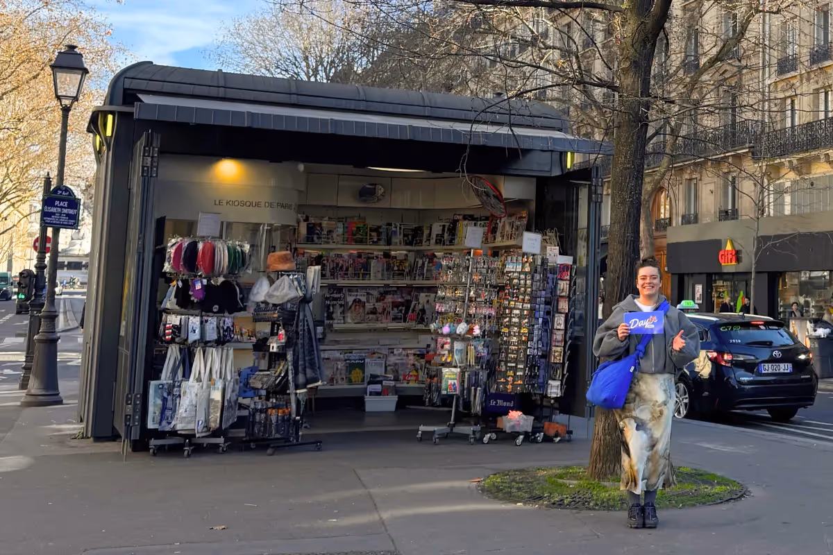 Guide holding a blue sign saying "Dayin" and "Connecting France" in front of a big and colorful glass-bubble modern sculpture.