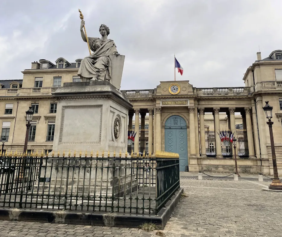 Guide holding a blue sign saying "Dayin" and "Connecting France" in front of a big and colorful glass-bubble modern sculpture.