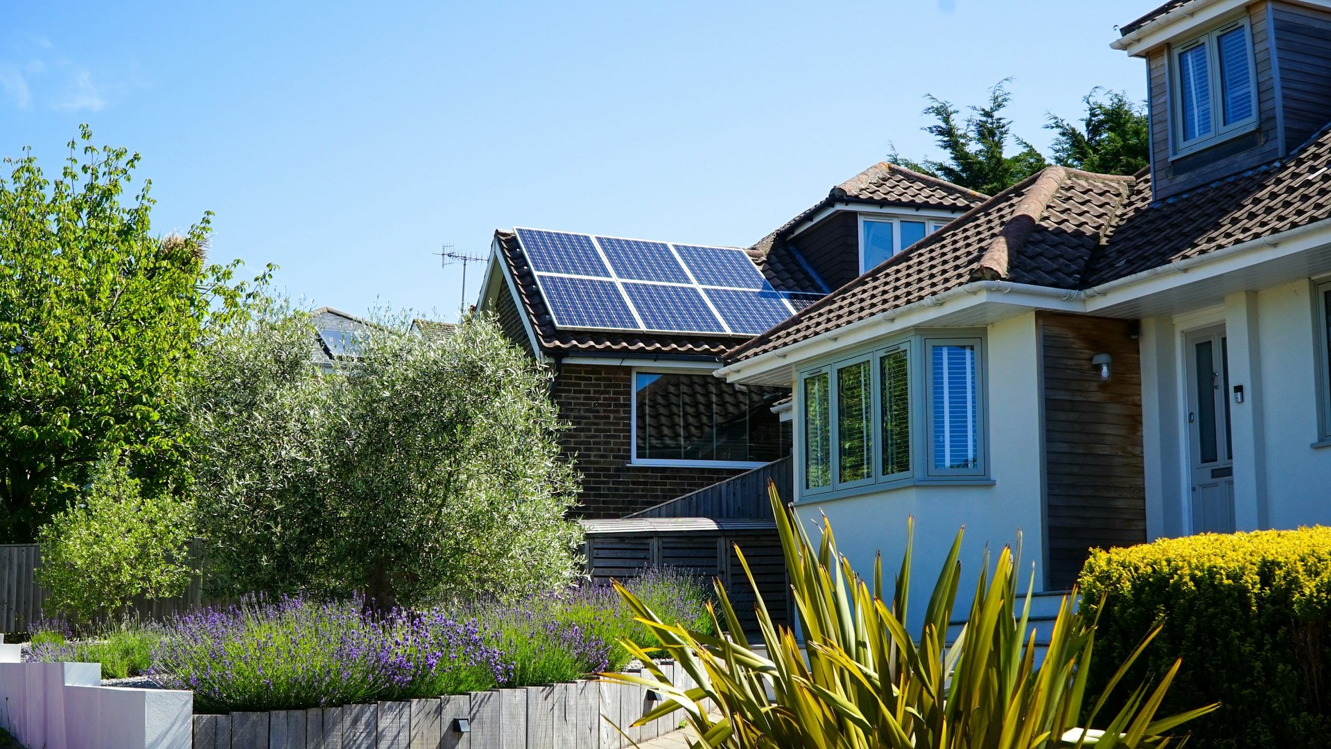 A suburban house with solar panels on its tiled roof on a sunny day