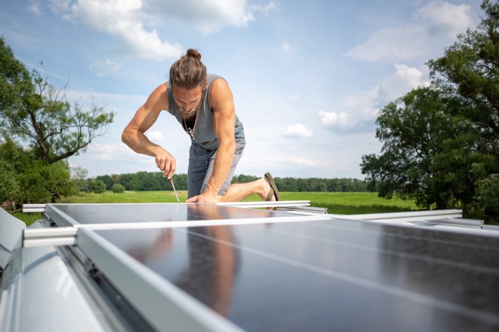man working on solar panels on caravan