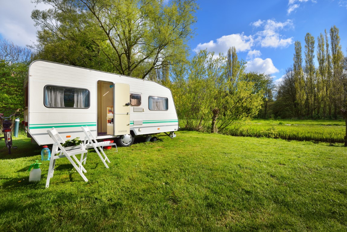 White caravan trailer on a green lawn in a camping site