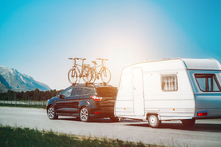 SUV Carrying Caravan and Bicycles on Highway. Summer Getaway