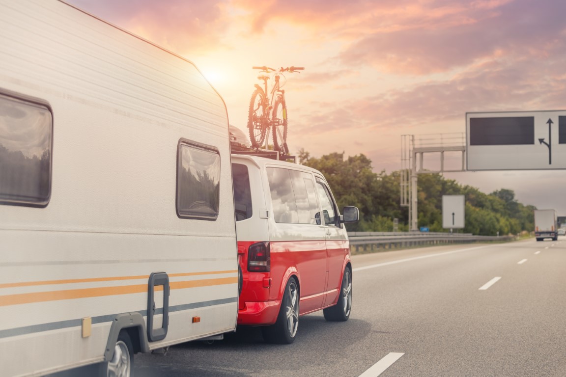 Scenic view big modern white family rv camper van vehicle driving on european highway road against sunset sun sky summer