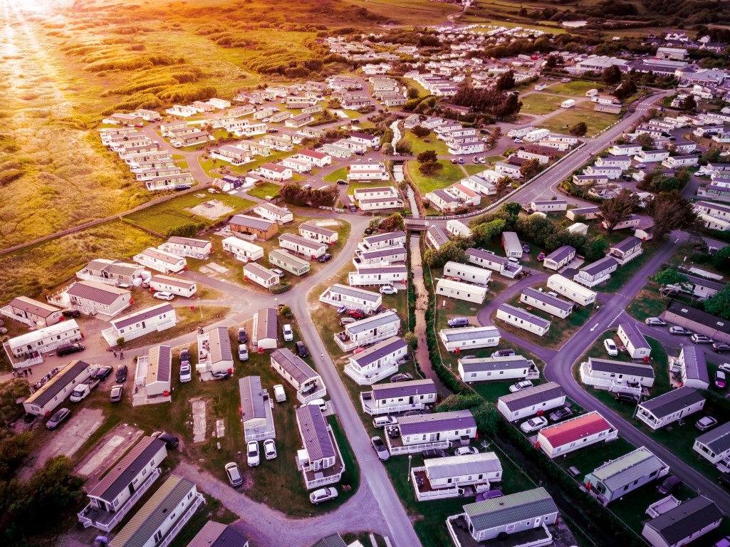 Sun Setting over the sea and Caravan and camping park, static home aerial view.