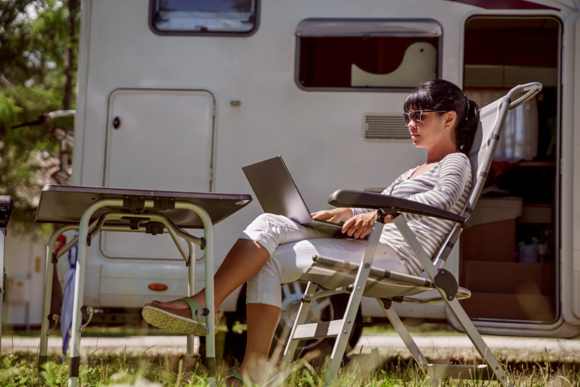 Woman looking at the laptop near the campsite