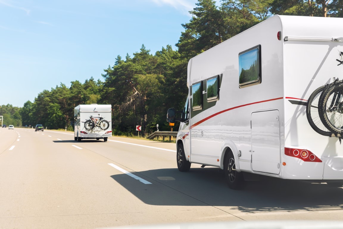 Scenic view big modern white family rv camper van vehicle driving on european highway road against blue sky in summer day