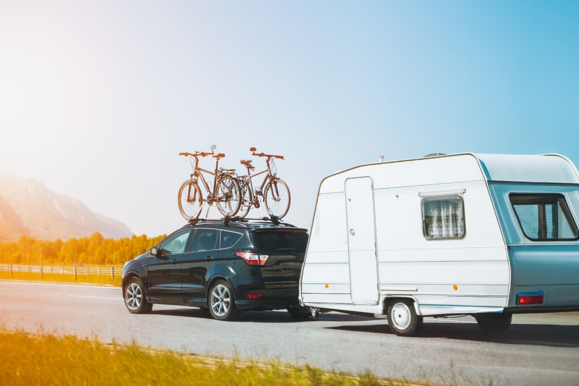 Car with bicycles, mounted on top towing a caravan