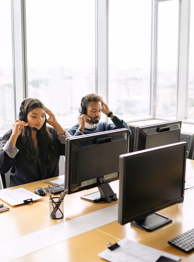 Man and woman in office with headphones working operations center support.