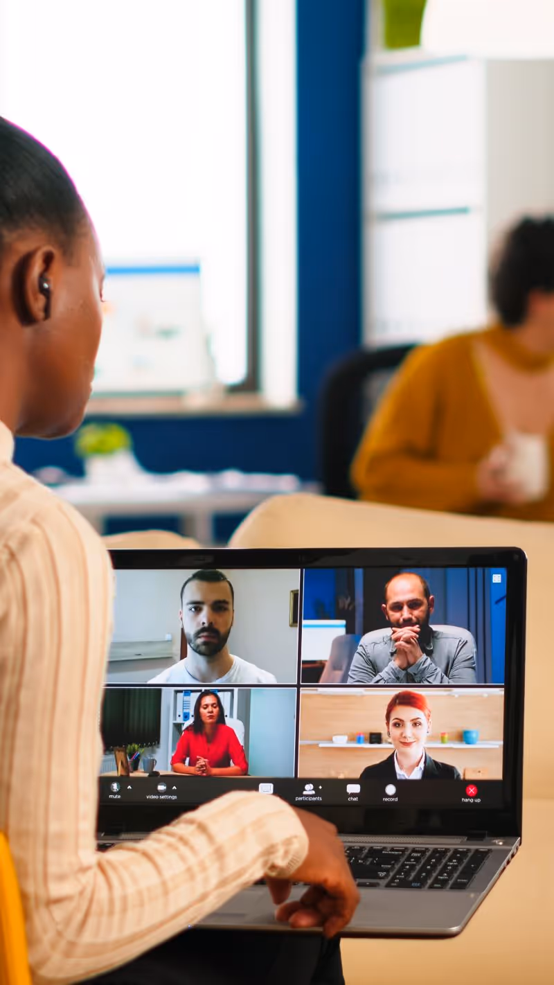 Business person working from home with computer screen showing team members remotely