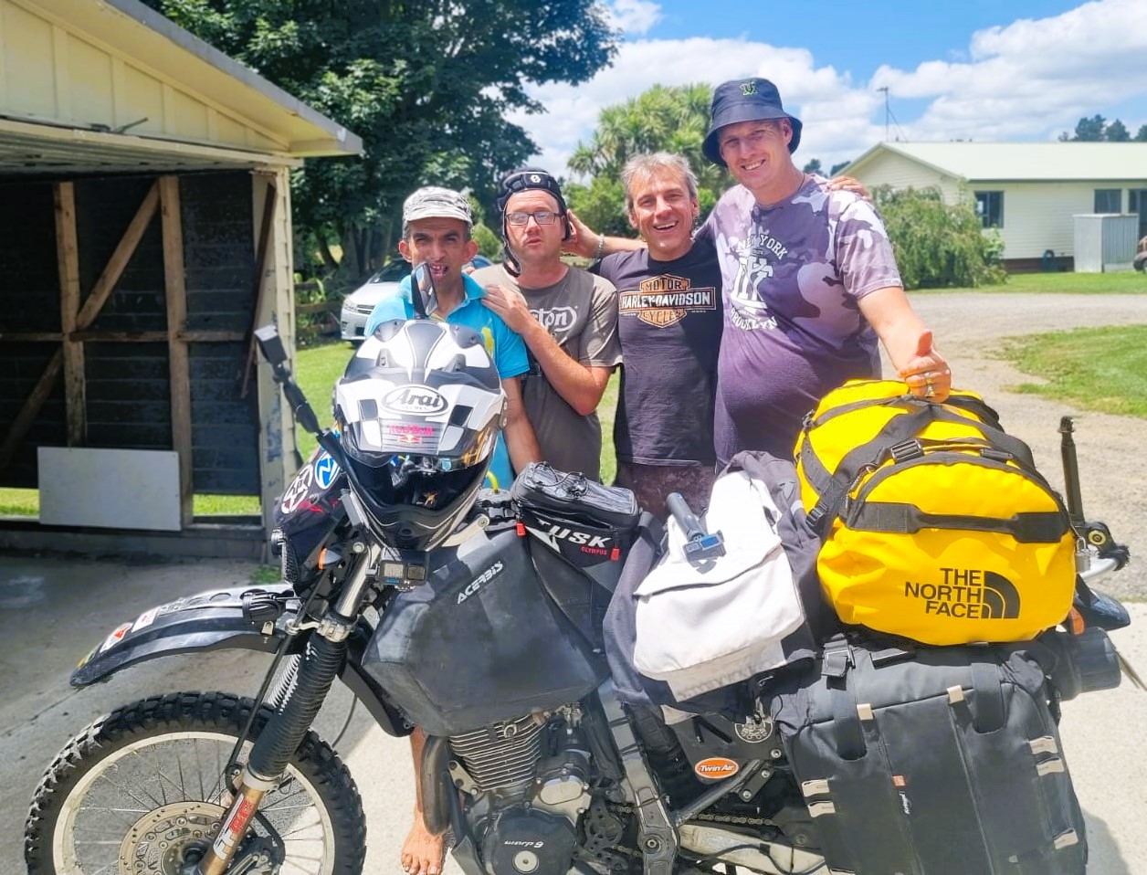 Ray Urlich pictured standing with people supported by IDEA Services, behind Ray's motorcycle.