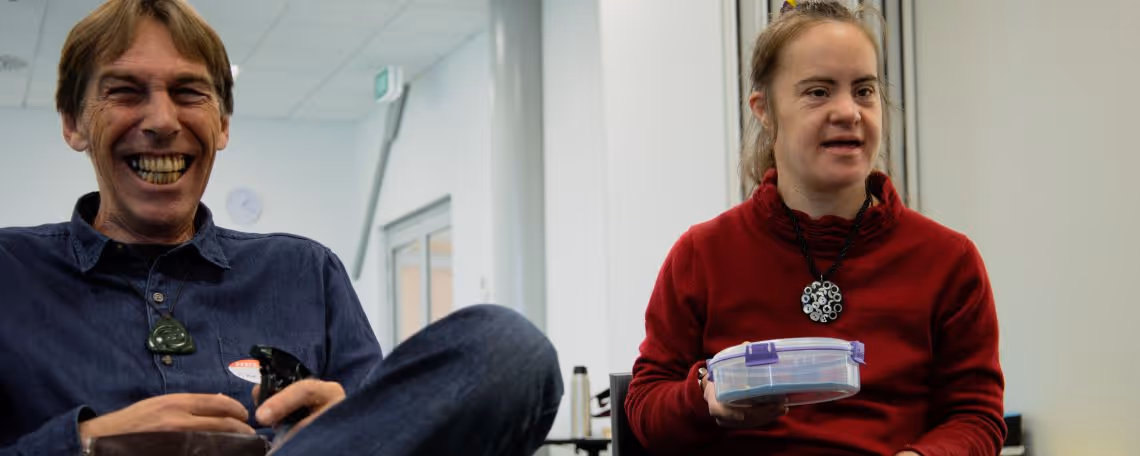 Two people sitting down  at a music therapy lesson and smiling