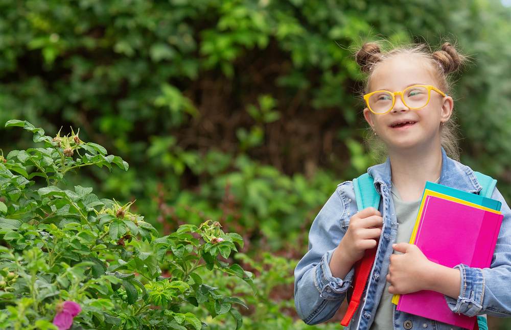 A girl with her school bag and folders walking outside
