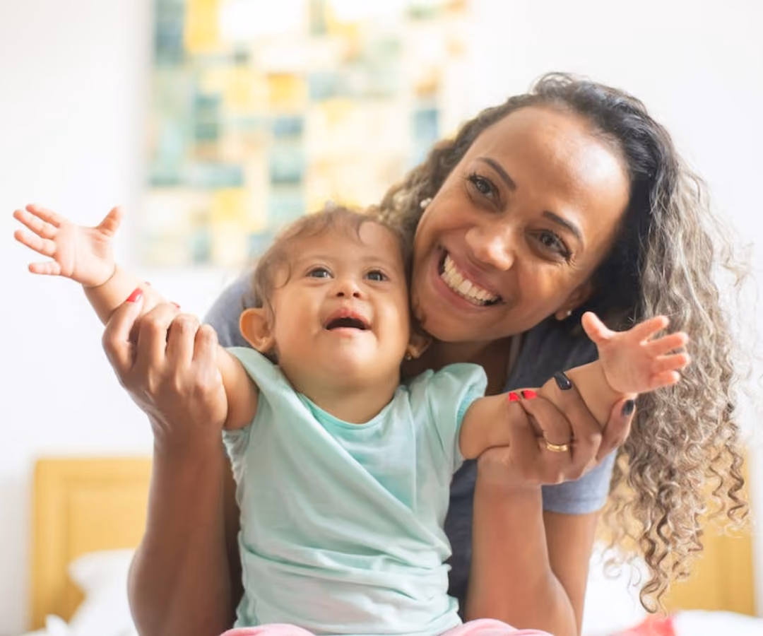 Little girl with her arms out with her mum holding her and smiling