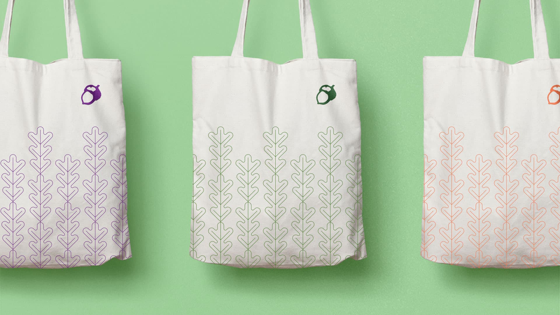 Doe-Anderson acorn logo on canvas tote bags in three colors: purple, green, and orange.
