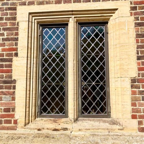 Close-up of the side of a traditional house with a set of wooden-framed windows.
