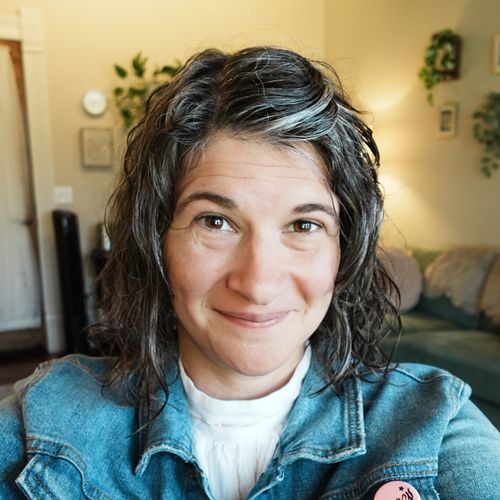 Therapist Malia Hagen smiles from her desk at her office in Round Rock, TX, with a couch and plants behind her.