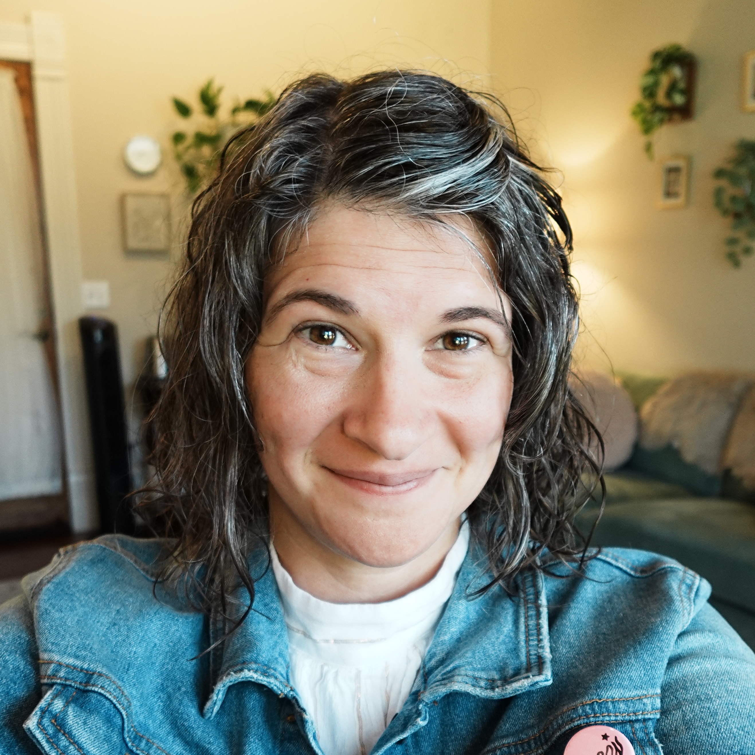 Therapist Malia Hagen smiles from her desk at her office in Round Rock, TX, with a couch and plants behind her.