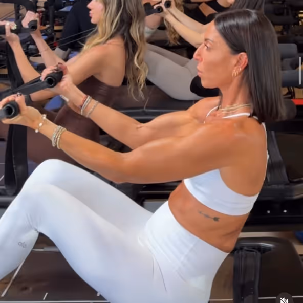Women performing rowing exercise on machines in a gym, focusing on upper body strength.