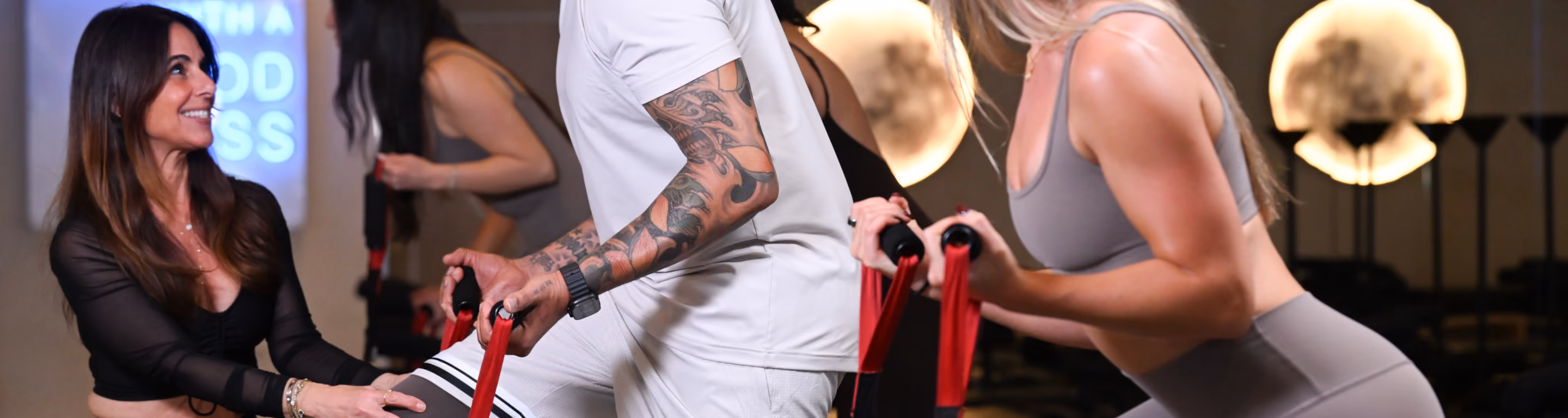 Fitness instructor guiding man and woman using resistance bands during workout session.