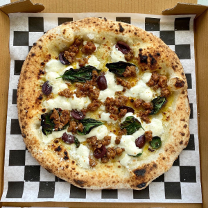 A white Neapolitan pizza with spicy sausage, kalamata olive, garlic, and basil.