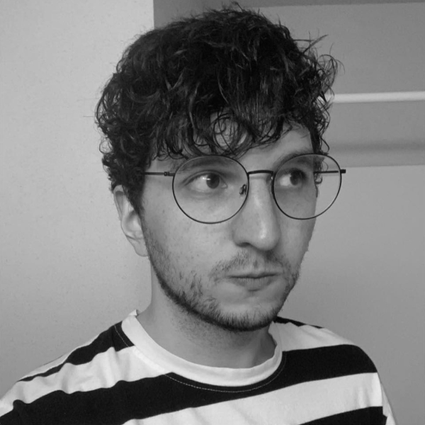 A photo of me.  Adult male, curly black hair, with large glasses, and short stubble, wearing a black and white striped tshirt.