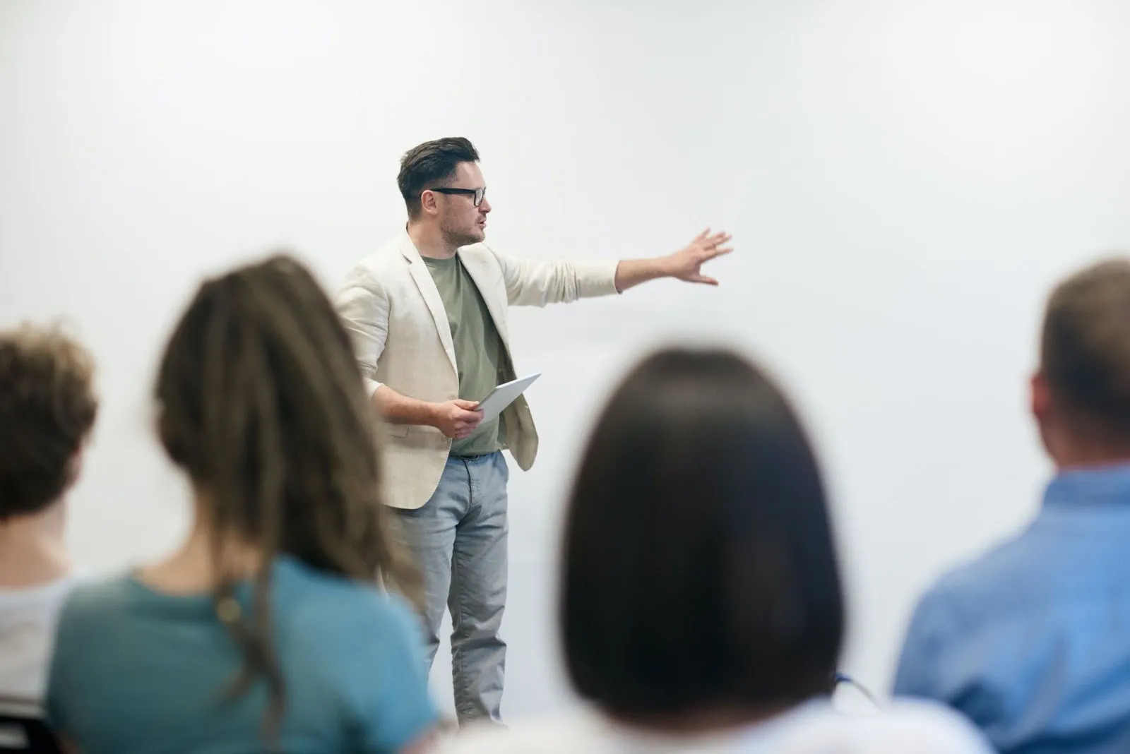 A teacher stands in front of a crowd with a notepad in his hand.