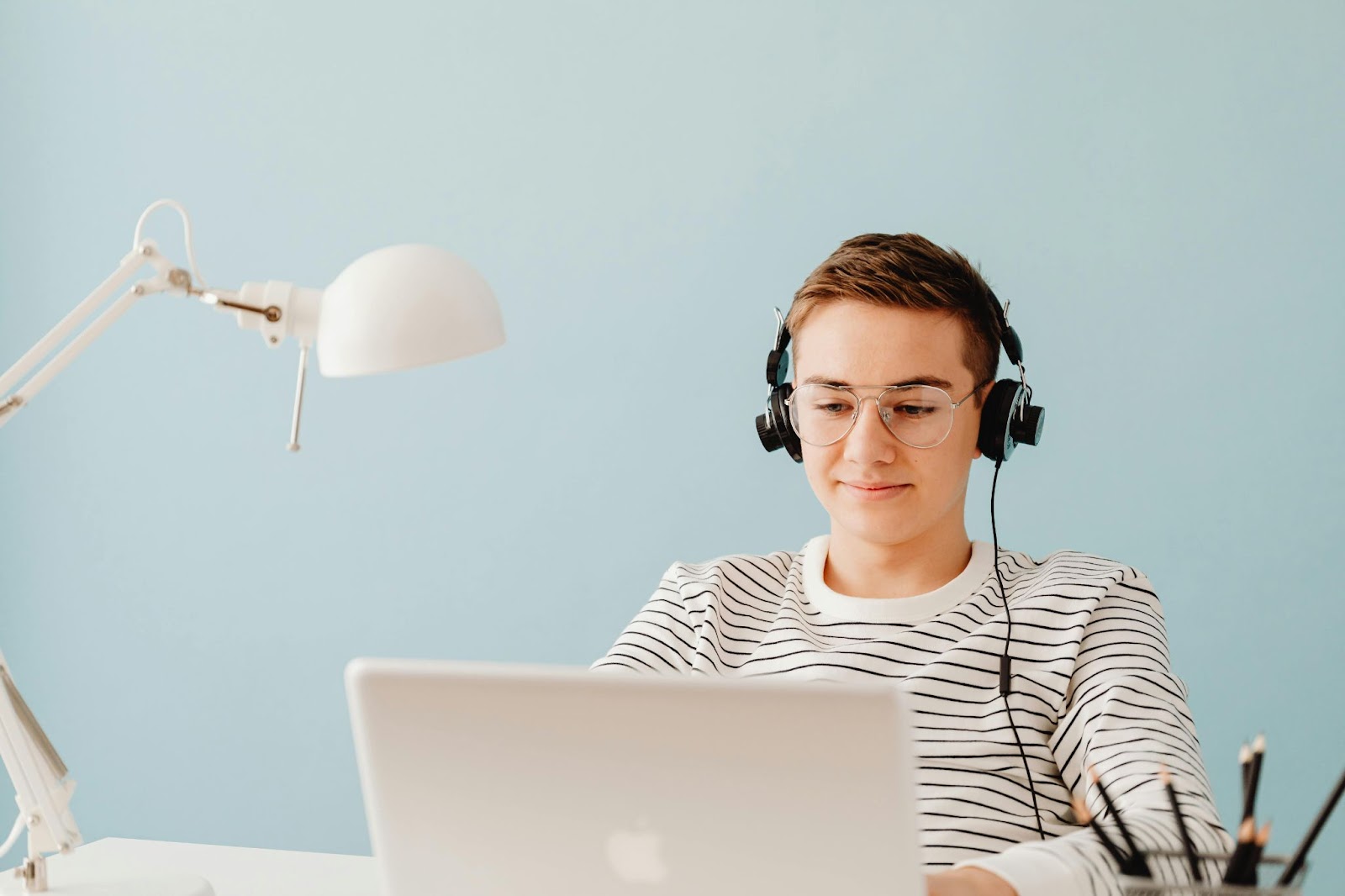 A student listens to over-the-earheadphones while working on their laptop.