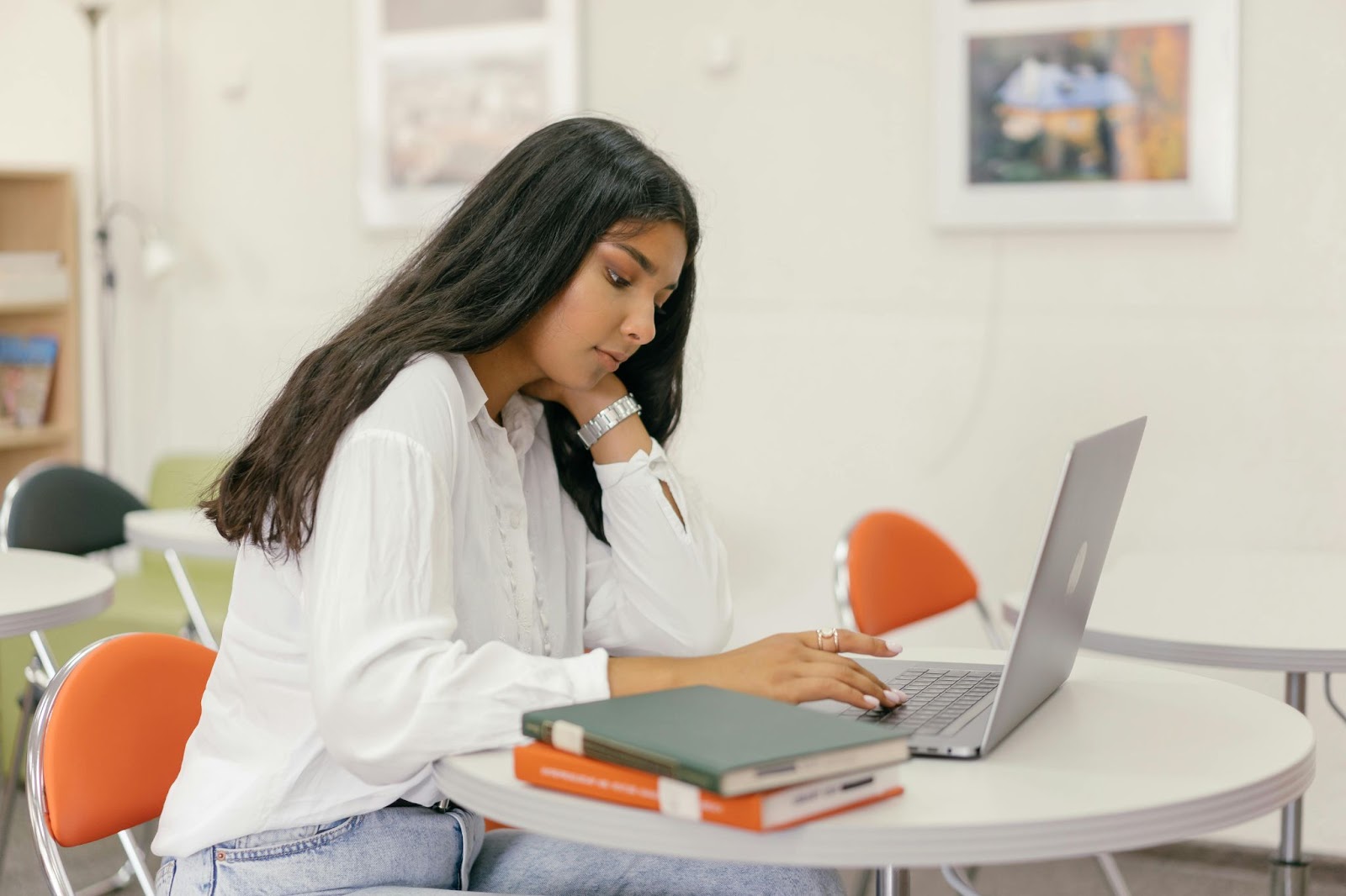 A student leans her head on her hand while completing classwork on her laptop.